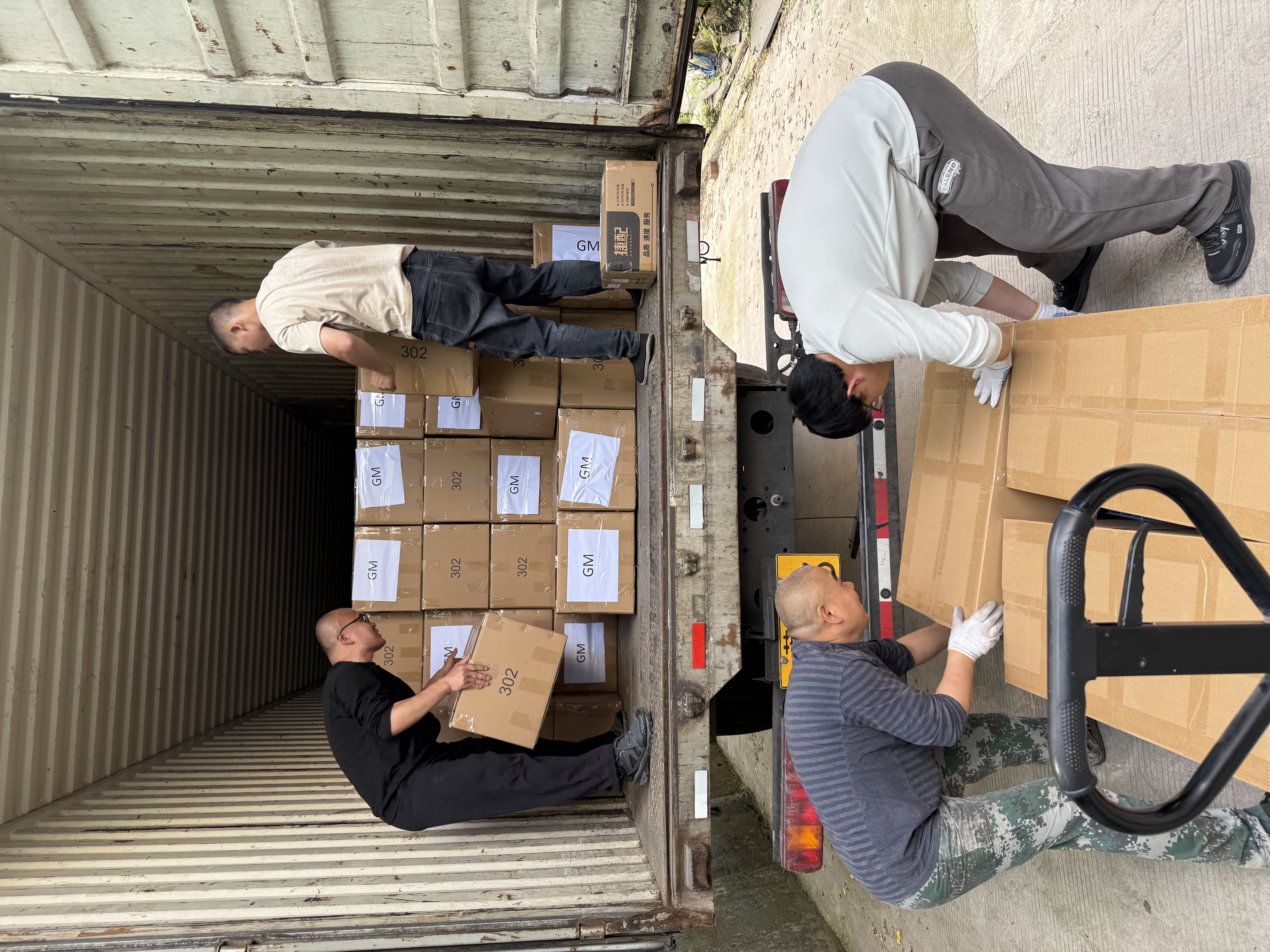 Workers loading traffic signal cartons into a shipping container